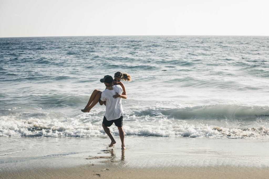 man carrying woman on seashore - secluded beaches