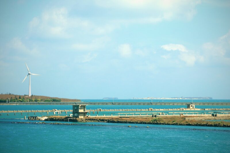 a large body of water with a wind turbine in the background