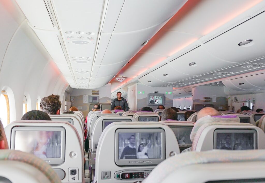 man walking down the aisle of airplane - fly more comfortably
