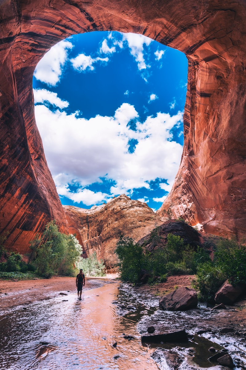 man walking under cave during daytime