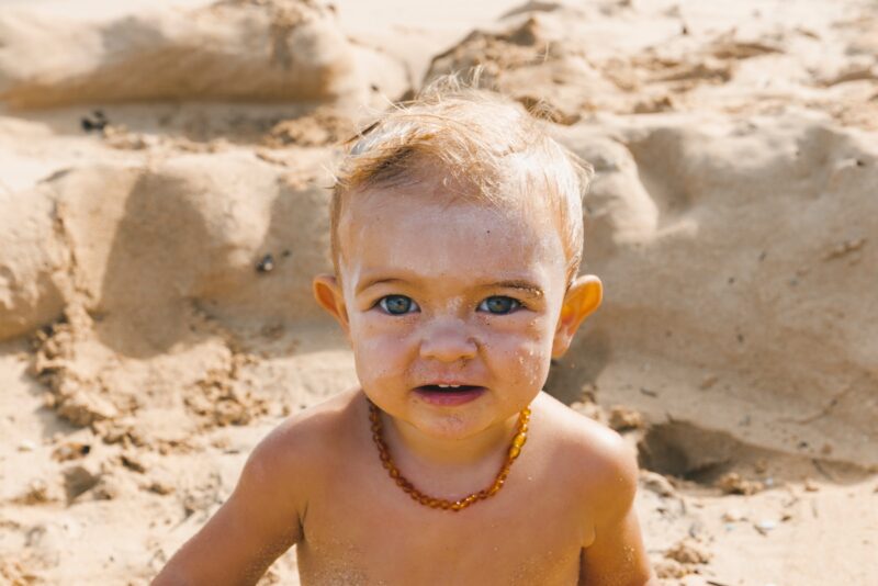 a little boy that is standing in the sand with sunscreen. Best sunscreen for kids