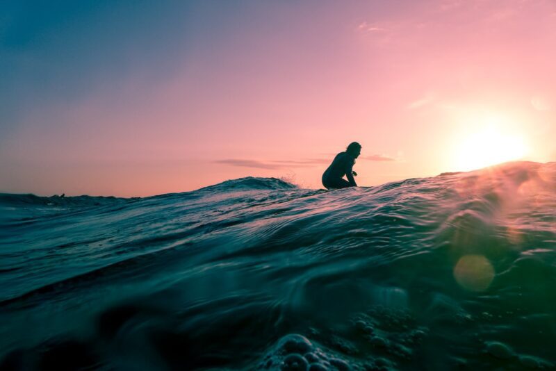 man surfing on ocean water during golden hour