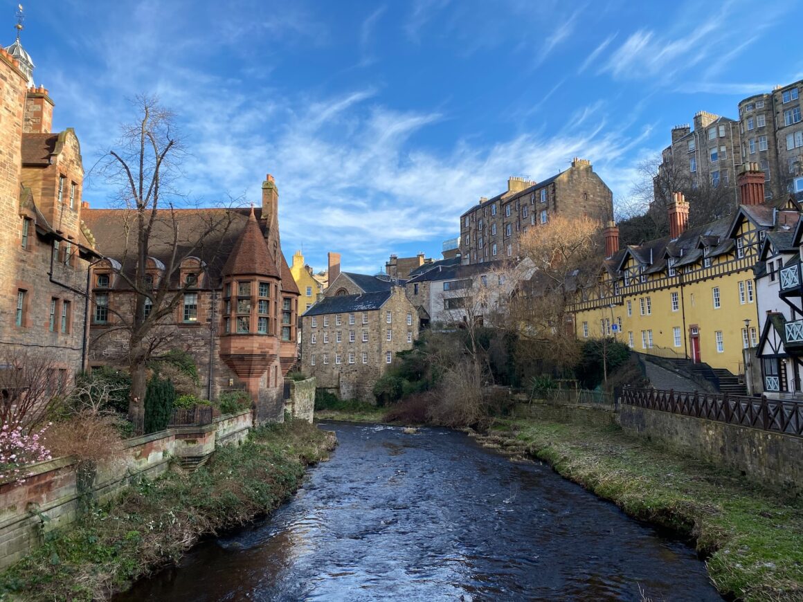 brown concrete building beside river under blue sky during daytime