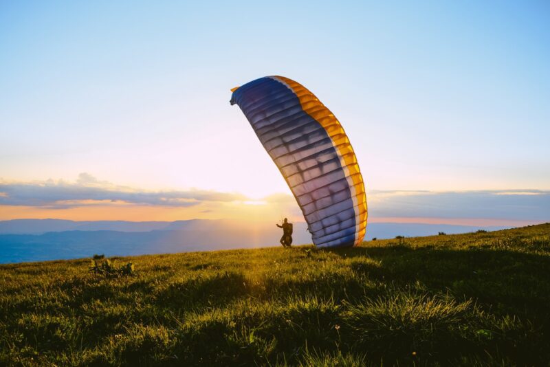 silhouette of person riding parachute during sunset