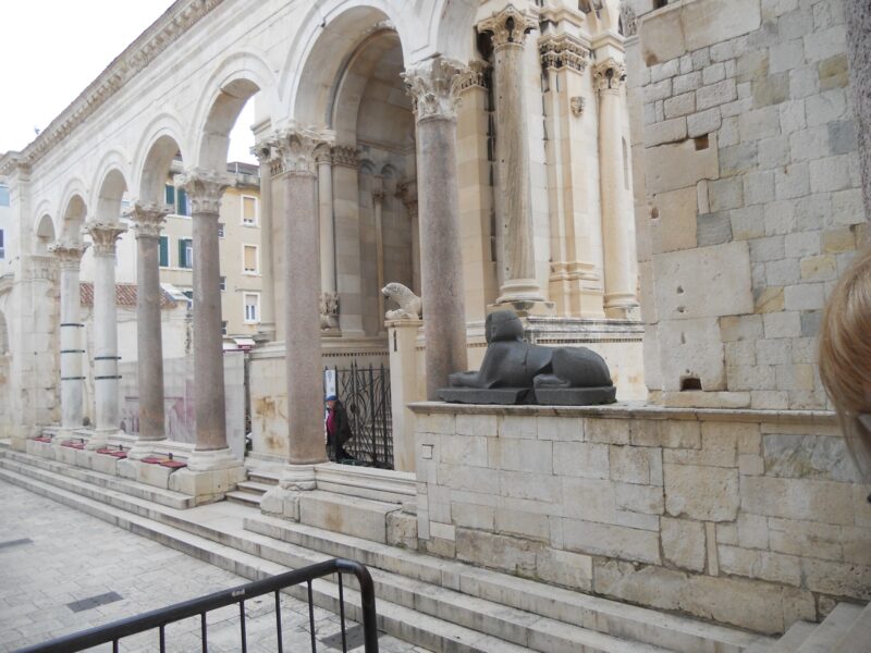 a woman standing next to a stone building