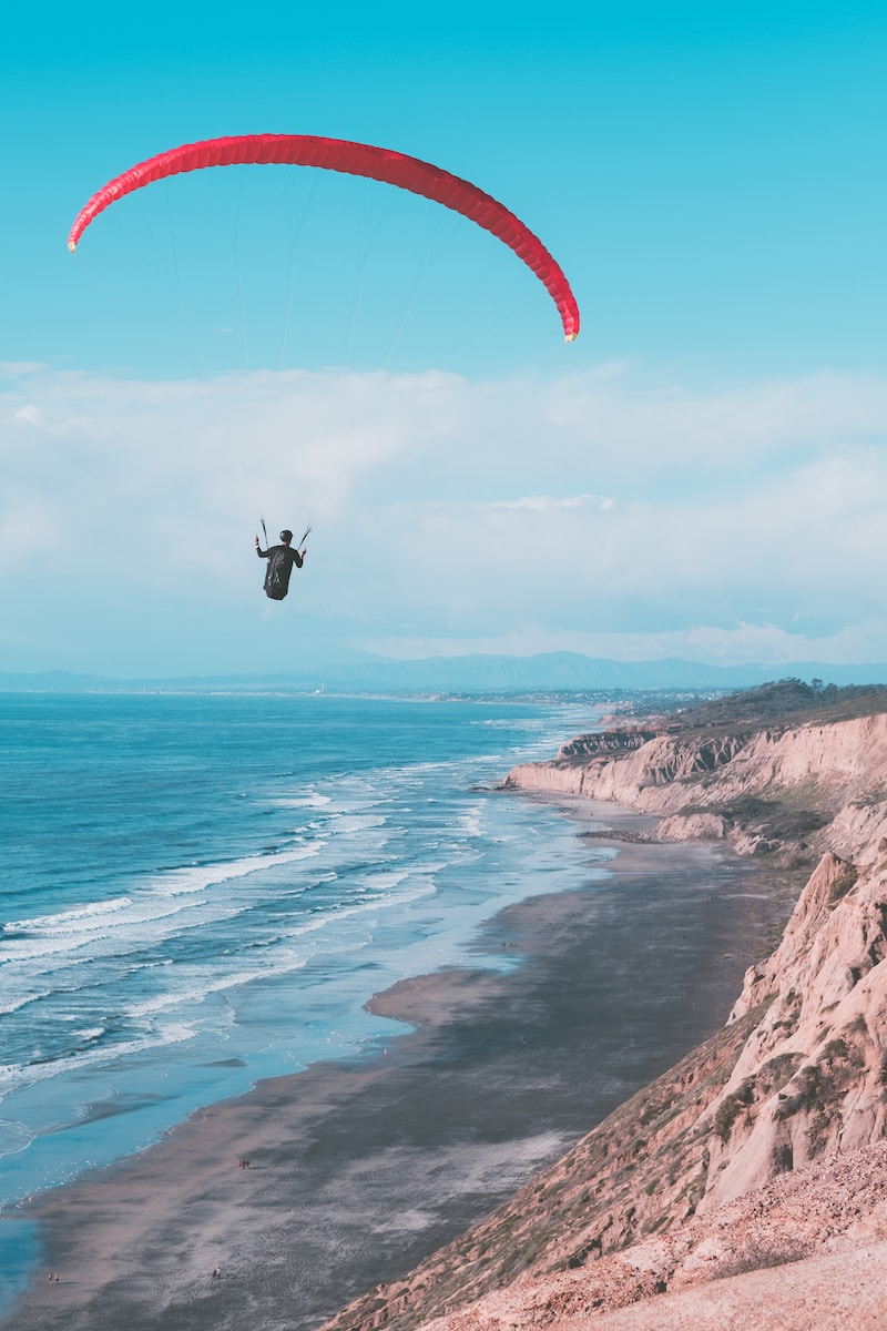 a person is hang gliding over the ocean on a sunny day