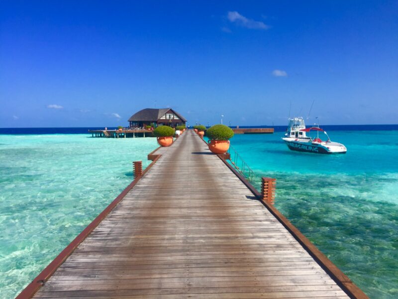 brown wooden dock beside white motor boat