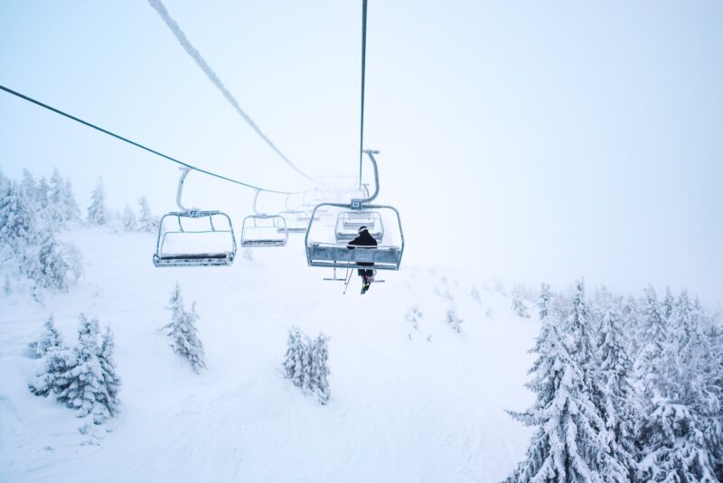 person riding cable train above snow covered field skiing destinations 