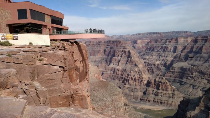 people standing on cliff under cloudy sky