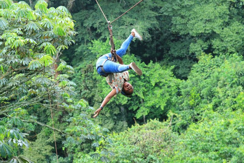 a man ziplining through a forest 