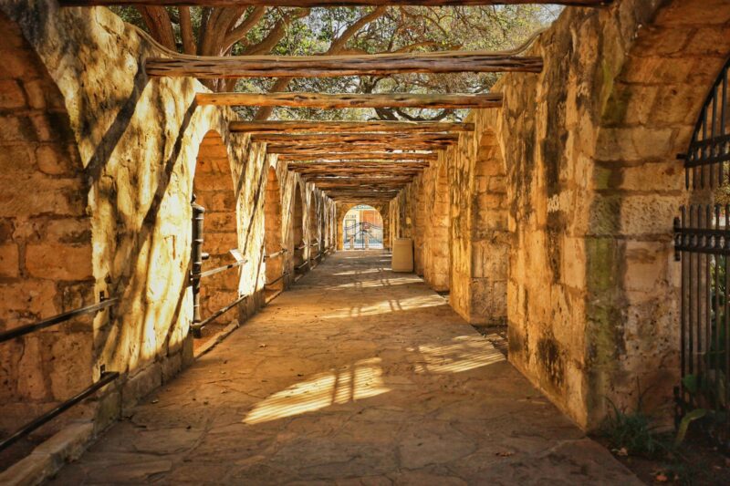 a tunnel of stone with a metal gate