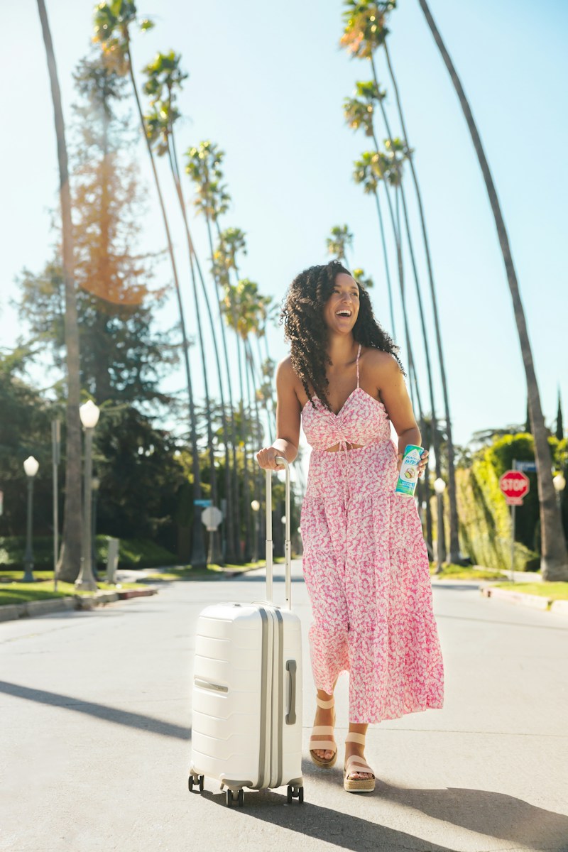 a woman in a pink dress pulling a suitcase