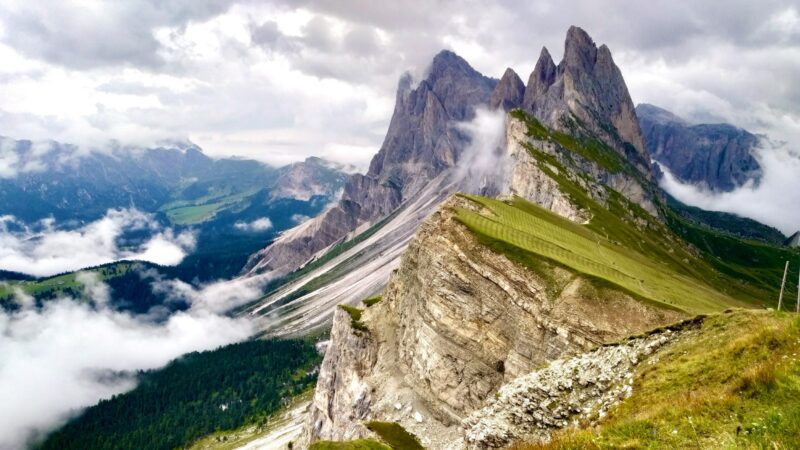 green grass on gray rocky mountain under white cloudy sky during daytime