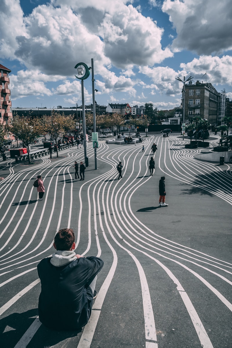 man in black jacket sitting on the road during daytime