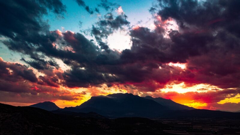 a sunset with clouds and mountains in the background