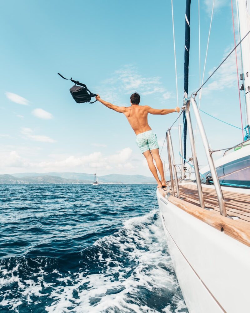 man wearing white shorts holding black backpack, sea travel